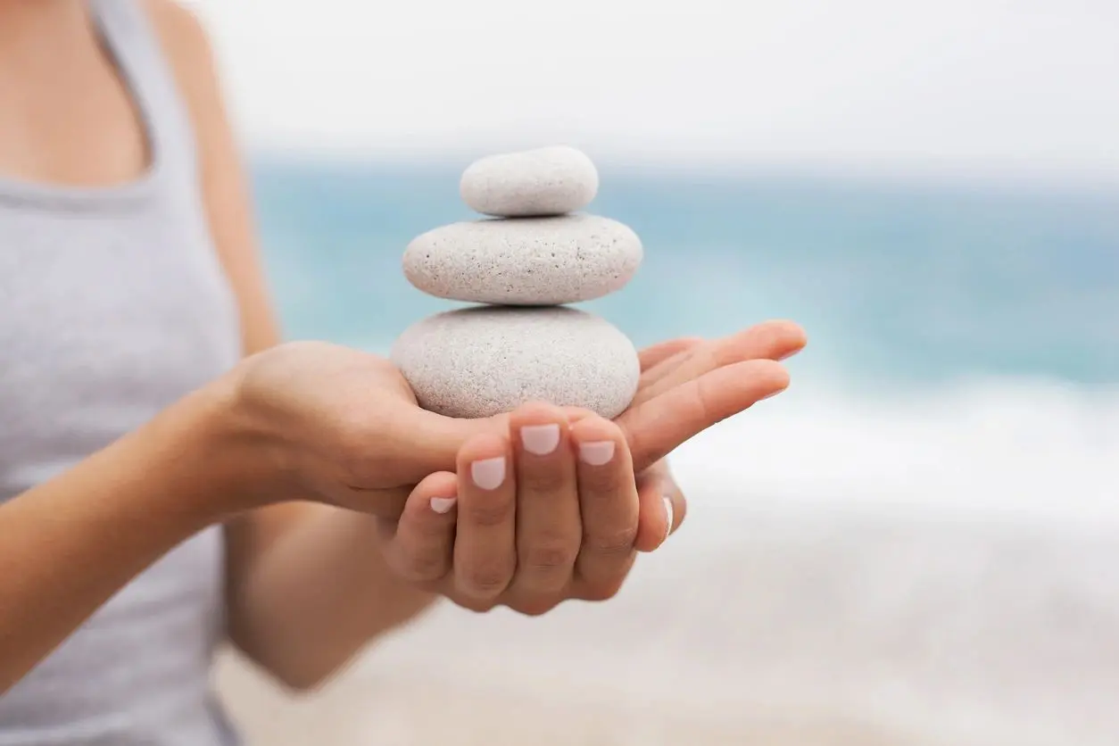 A person holding rocks in their hands on the beach