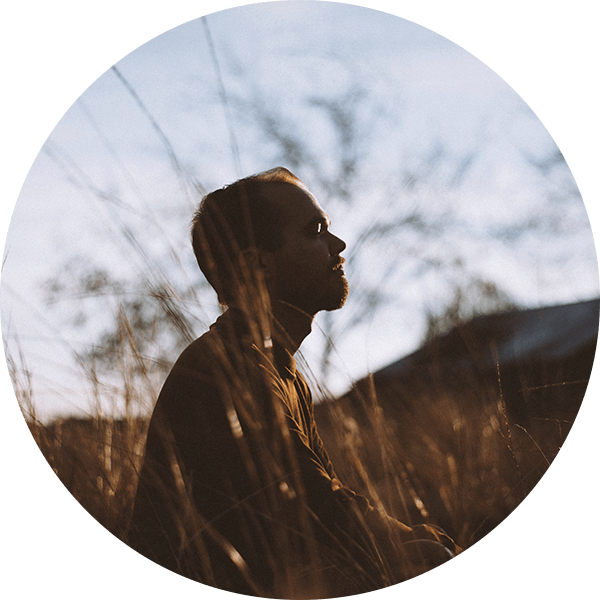 A man standing in the grass looking up.